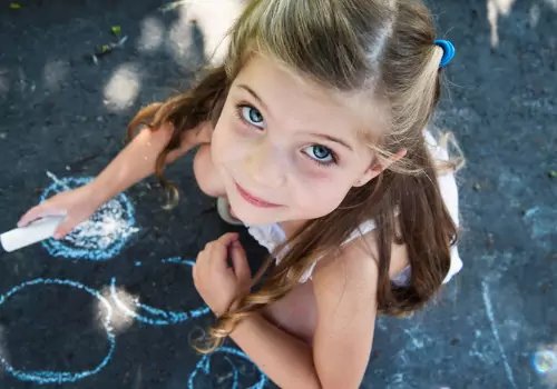 A child is seen drawing on fresh asphalt. Berchtold Asphalt performs paving in Princeton IL.