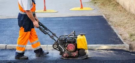 Worker padding down asphalt