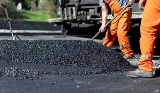 Road workers laying down asphalt