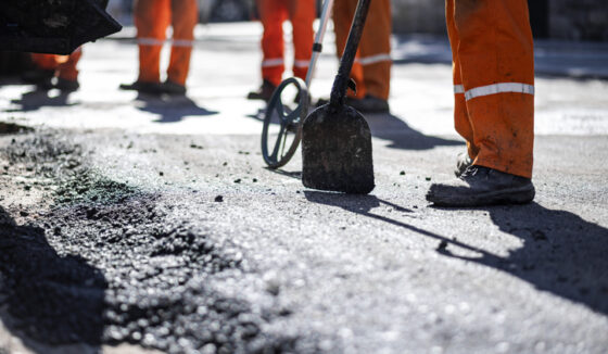 Construction crews are actively repairing a section of roadway using shovels and other tools as part of LaSalle-Peru asphalt services